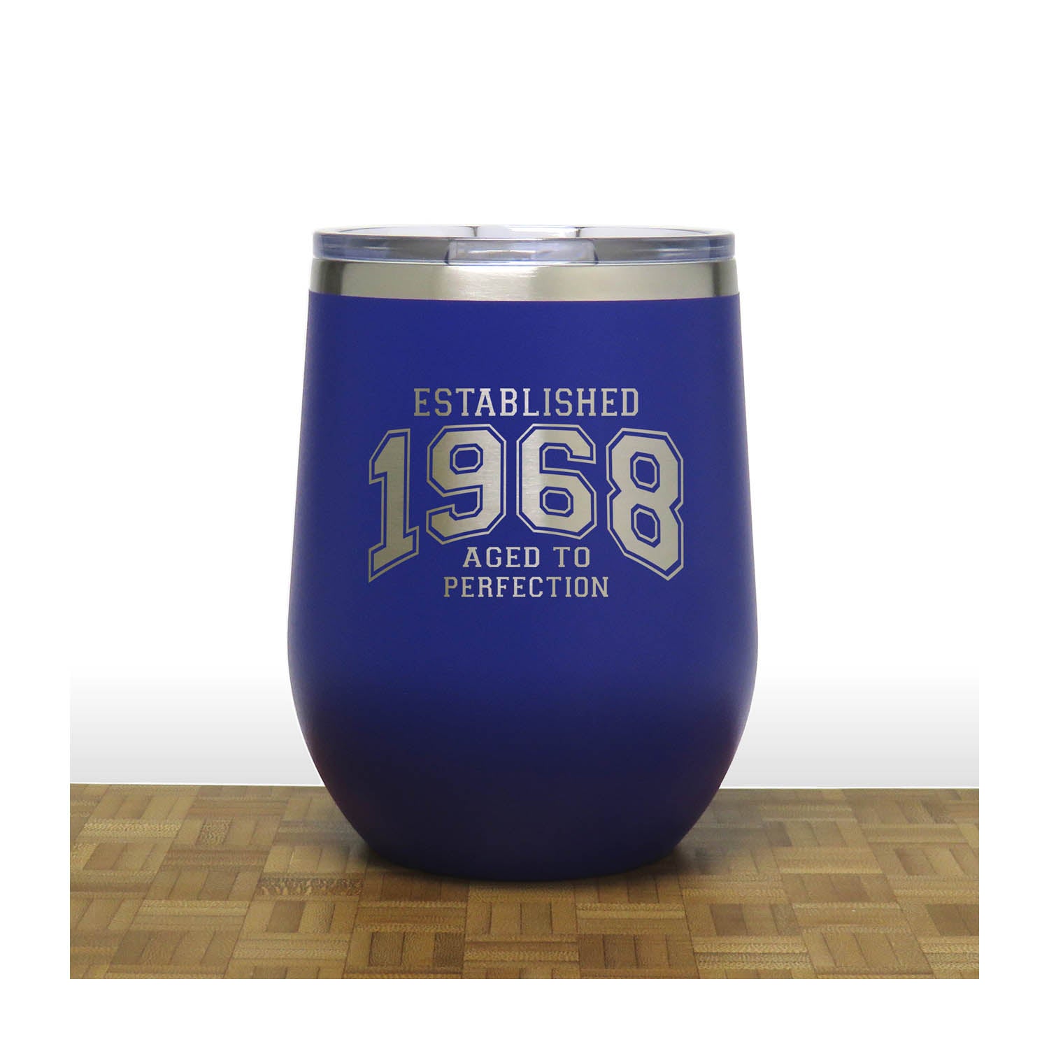 Blue wine tumbler with 'Established 1968 Aged to Perfection' text on a wooden surface.