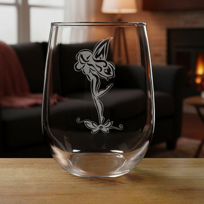 Clear glass with a fairy design on a wooden surface and black couch in the background
