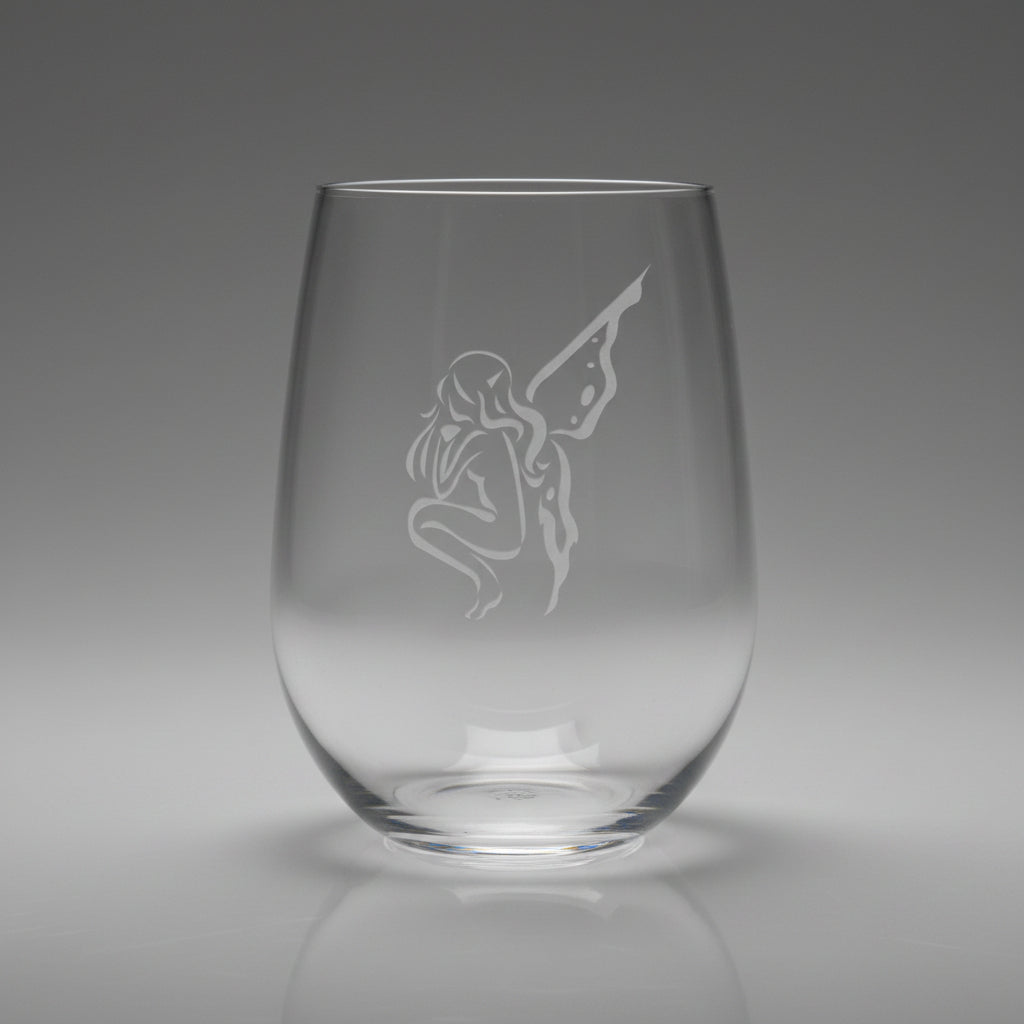 Clear glass with an engraved fairy design on a wooden surface 