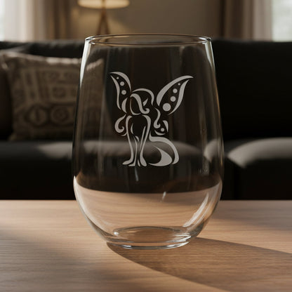 Clear glass with a fairy design on a wooden surface and black couch in the background