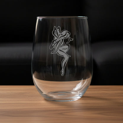 Clear glass with a fairy silhouette etching on a wooden surface and black couch  background