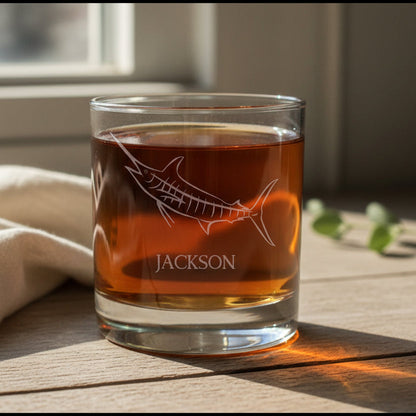 A clear rocks glass filled with an amber-red drink, featuring an etched marlin design and the name 'JACKSON' on the front