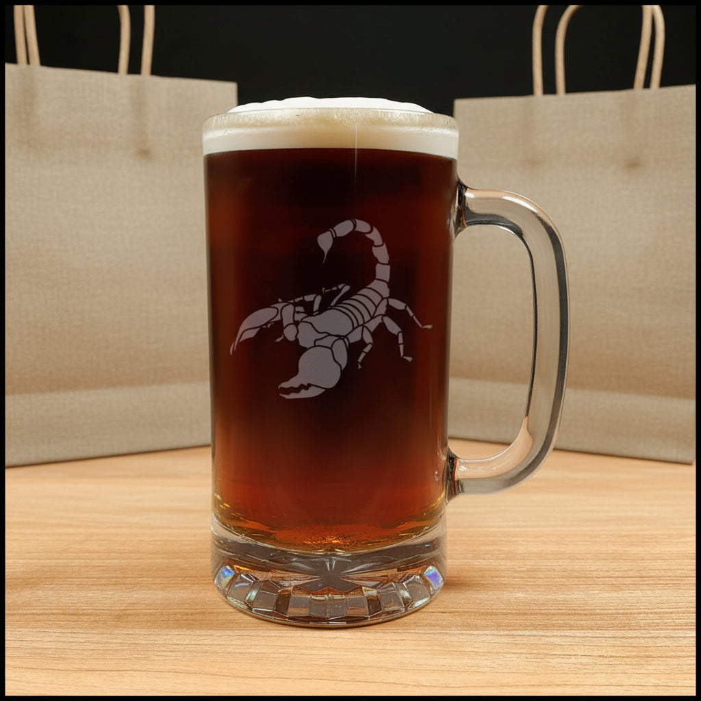 A clear glass beer mug filled with dark amber beer, topped with white foam, featuring an etched scorpion graphic on the front.
