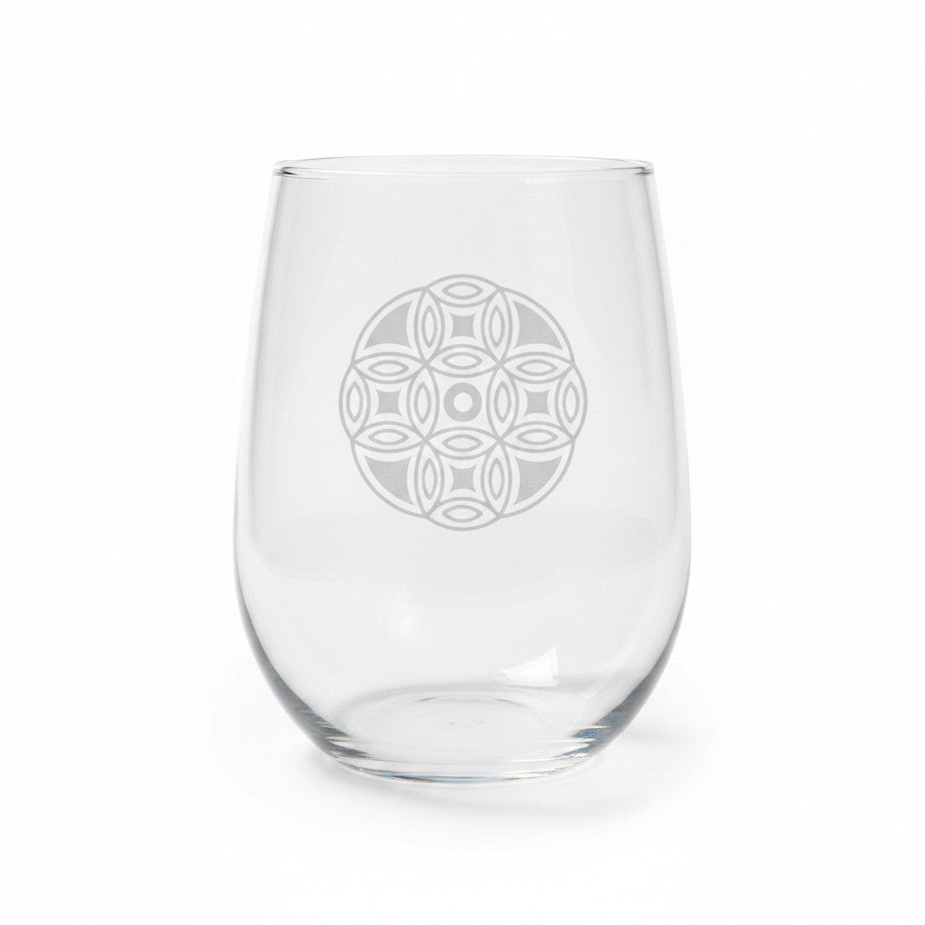 A clear stemless wine glass with a mandala etched design on the front, shown against a plain white background.