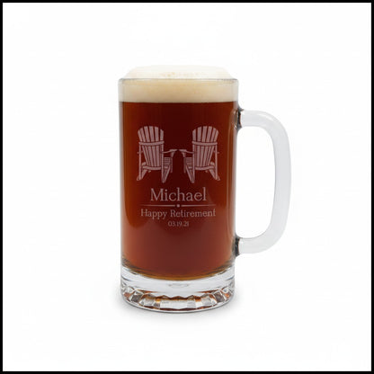 A clear glass beer mug filled with amber beer and topped with white foam, featuring a handle on the right. The front is engraved with two Adirondack chairs, the name 'Michael', and 'Happy Retirement 03.
