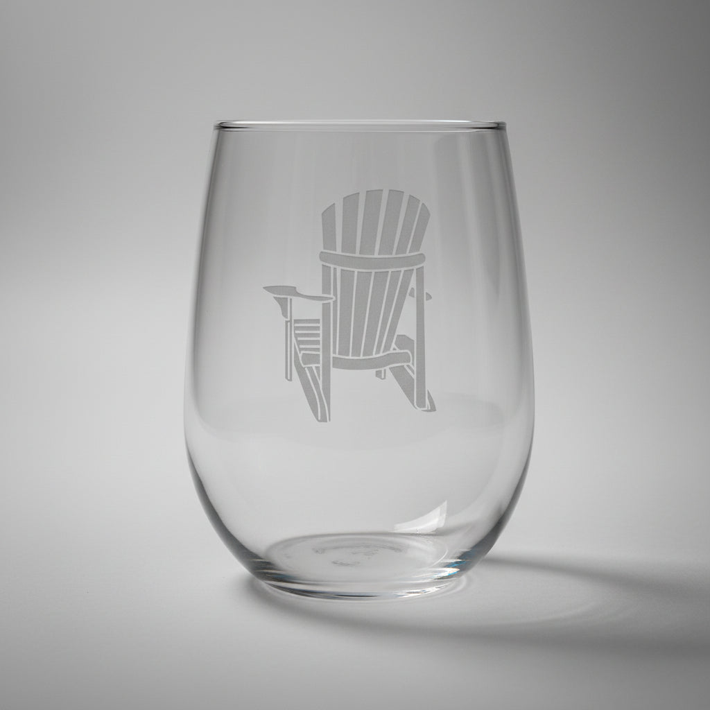 Clear glass with an engraved Adirondack chair design on a wooden surface and light grey background