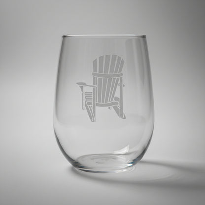 Clear glass with an engraved Adirondack chair design on a wooden surface and light grey background