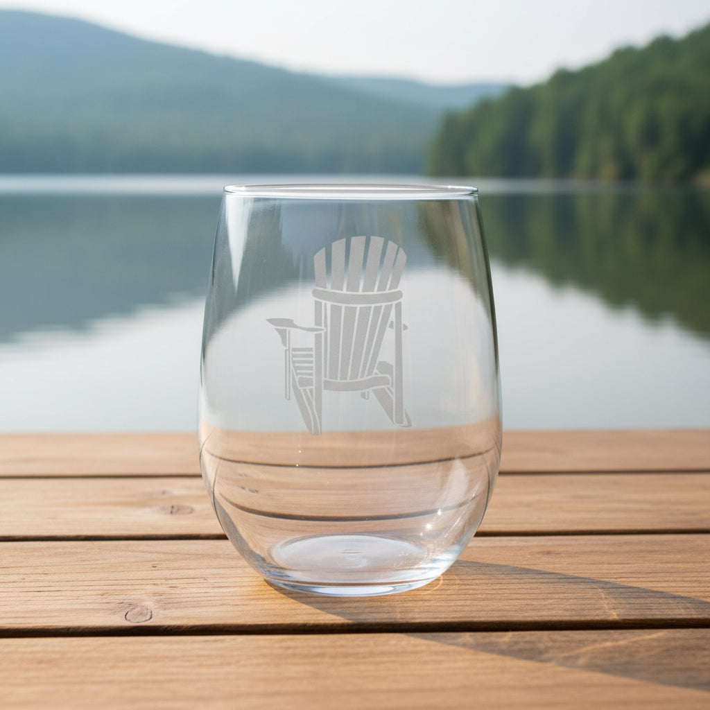 Clear glass with an Adirondack chair etching on a wooden surface with a lake in the background
