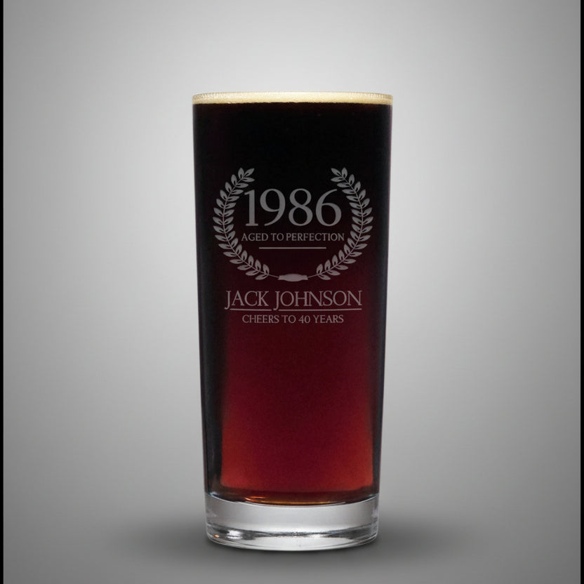 Glass with engraved text '1986 Aged to Perfection Jack Johnson Cheers to 40 Years' on a gray background