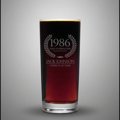 Glass with engraved text '1986 Aged to Perfection Jack Johnson Cheers to 40 Years' on a gray background
