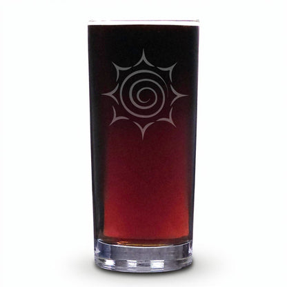 A tall, slender clear glass tumbler filled with a dark reddish-brown liquid, featuring a white etched spiral sunburst design on the front, set against a plain white background.