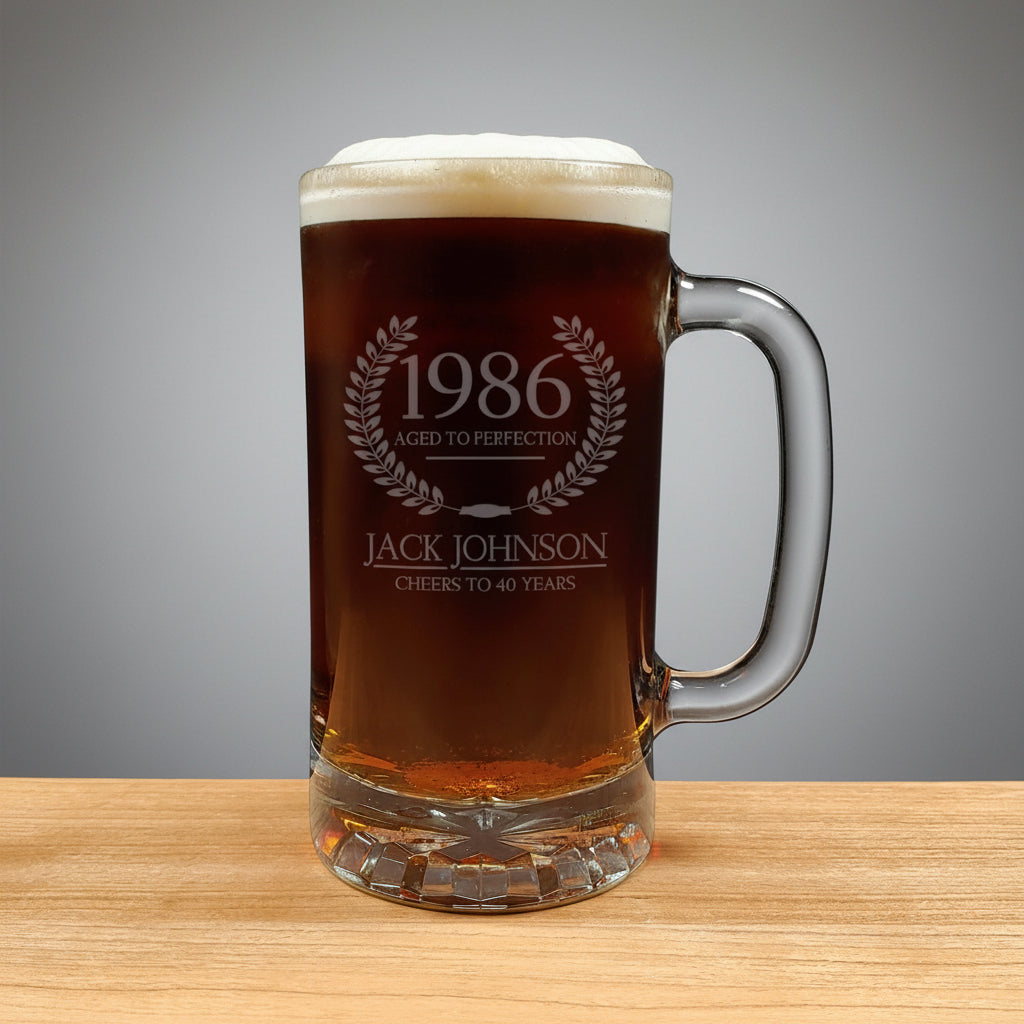 Glass mug with beer and engraved text on a wooden surface