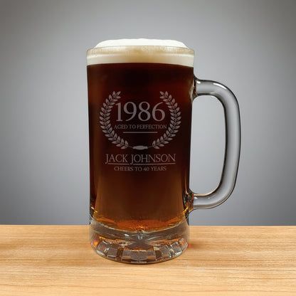 Glass mug with beer and engraved text on a wooden surface