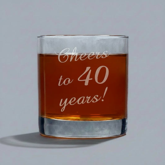 Glass tumbler with red liquid and 'Cheers to 40 years!' text on a gray background