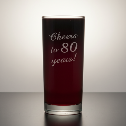 Glass with red liquid and 'Cheers to 80 years!' text on a white background