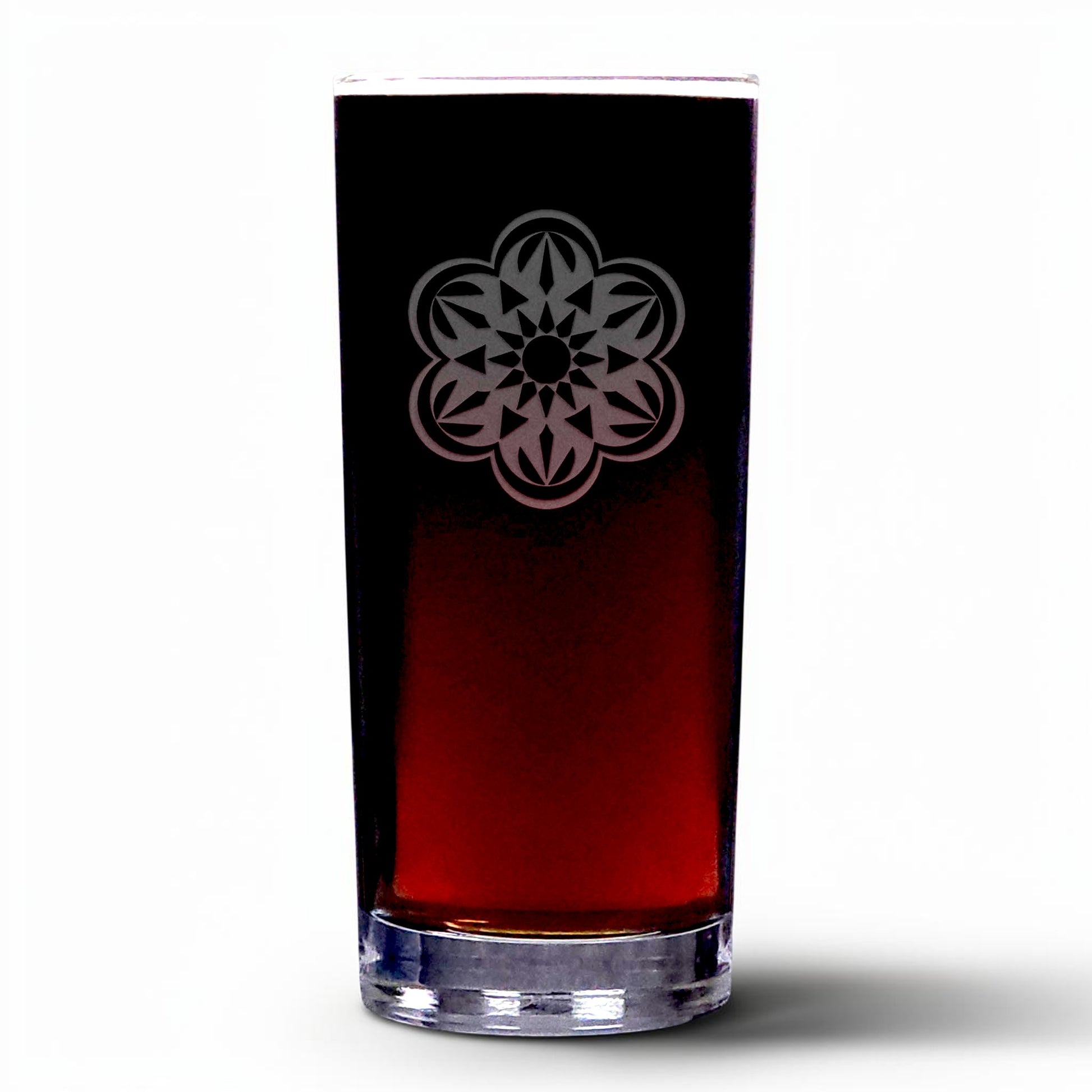 A clear highball glass with an etched floral mandala design on the upper half, shown filled with a dark red beverage 