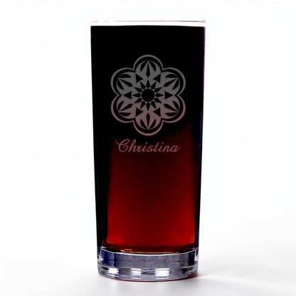 A clear highball glass with a dark red liquid inside, featuring an etched floral mandala design and the name 'Christina' in cursive near the top. The glass is photographed on a clean white background.