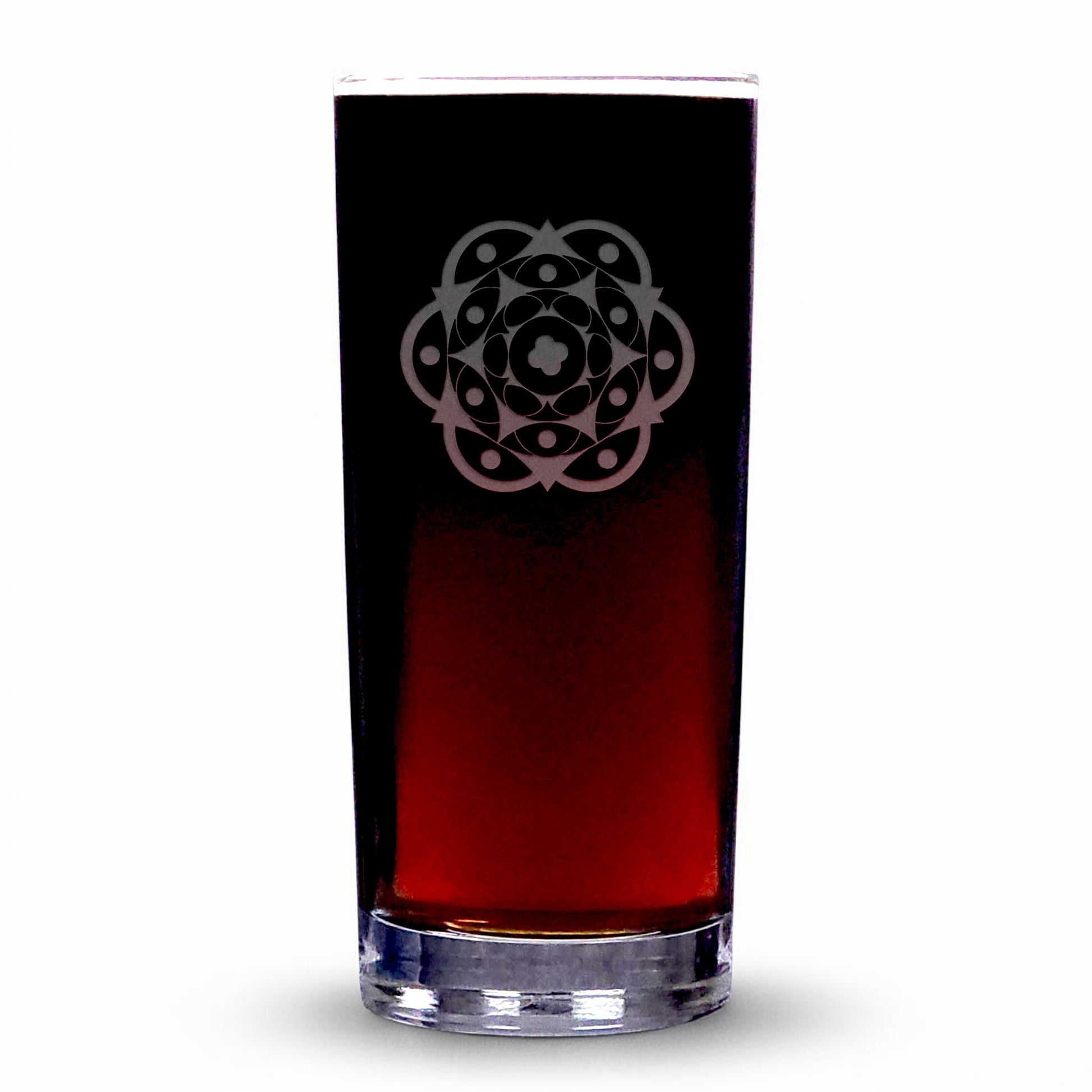A clear highball glass with a etched geometric floral mandala pattern on the upper half, filled with a dark red liquid, set against a plain white background.