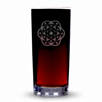 A clear highball glass with a etched geometric floral mandala pattern on the upper half, filled with a dark red liquid, set against a plain white background.