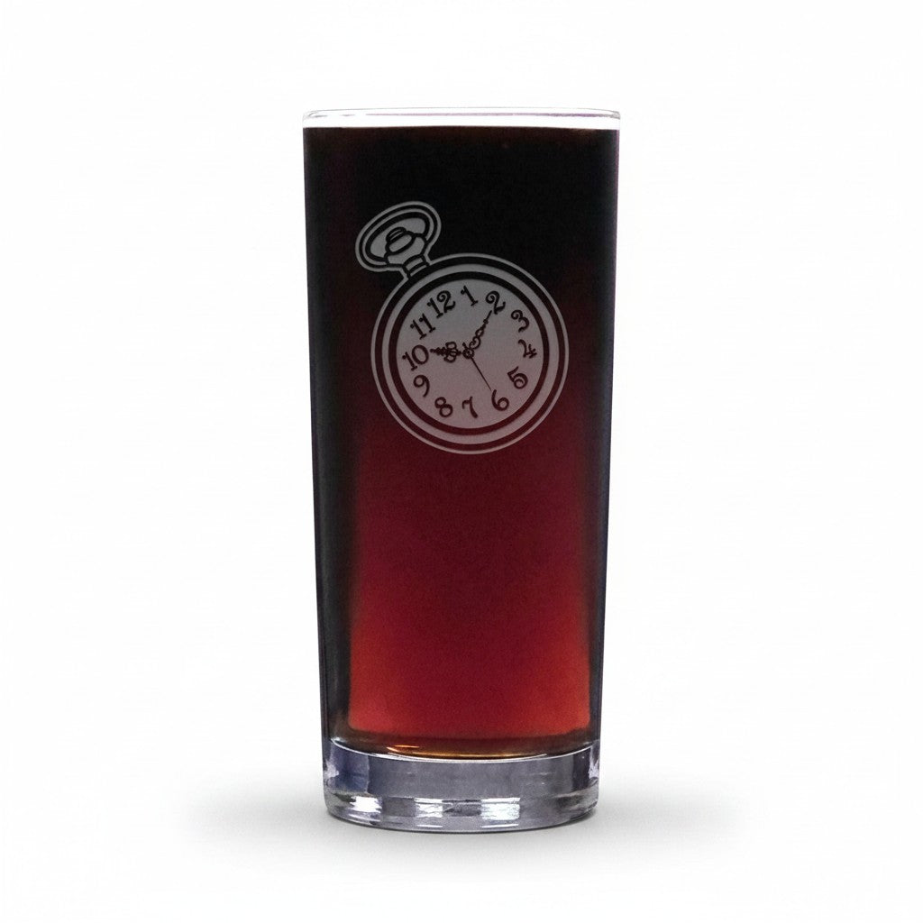 A clear highball glass filled with a dark red beverage, featuring an etched pocket watch design on the front, set against a plain white background.