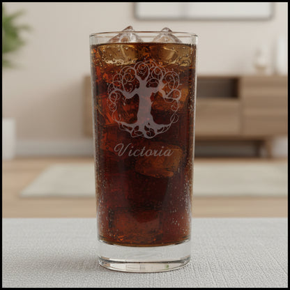 A clear cooler glass filled with dark drink, featuring an etched tree of life design and the name 'Victoria' on the front, set against a neutral background.