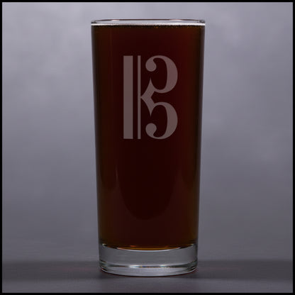 Cooler glass with a alto clef etching on a gray background