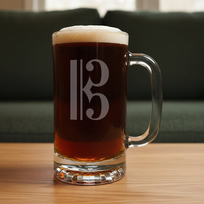 Glass mug with a alto clef engraving filled with dark beer on a wooden surface with a green couch in the background