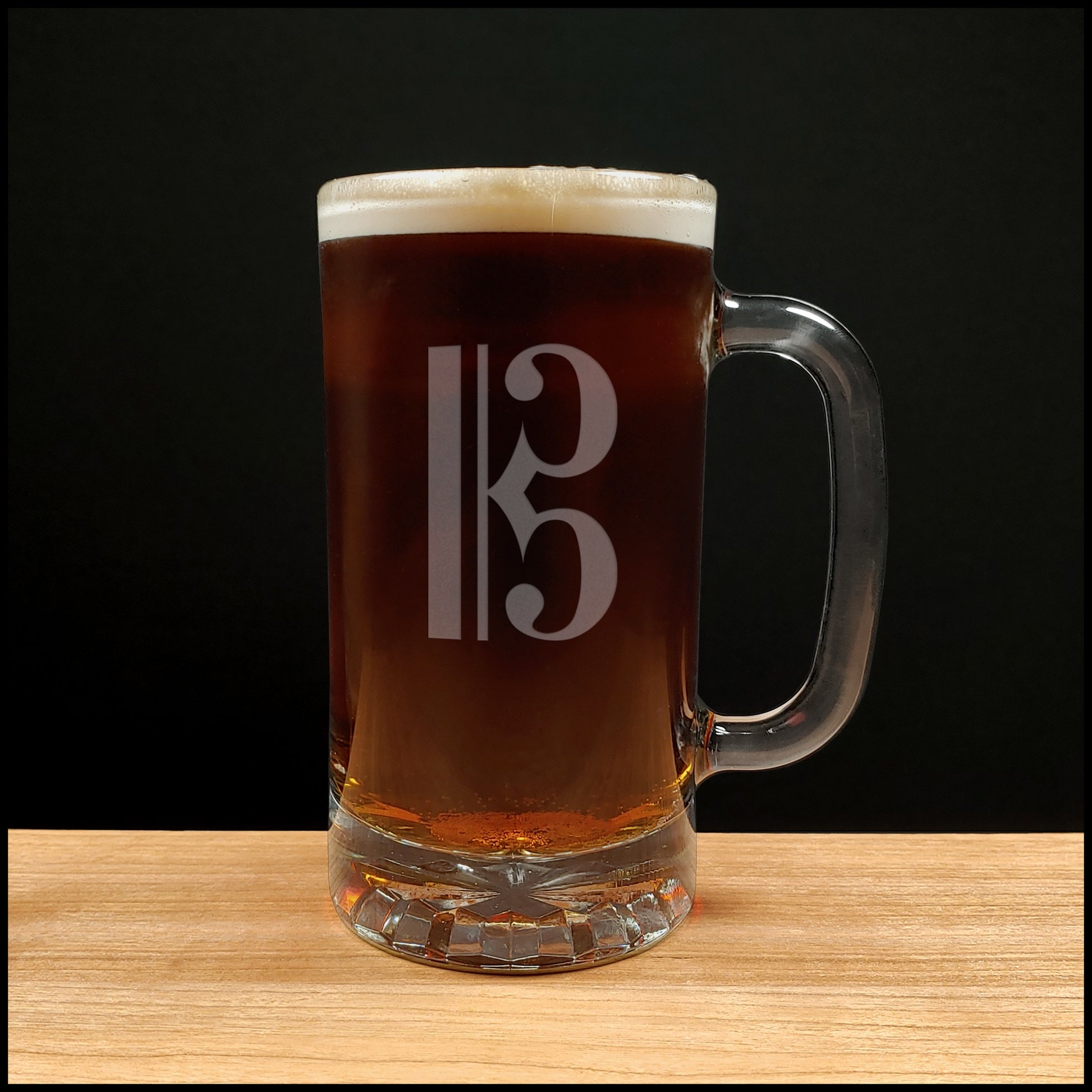 Glass mug with a treble clef engraving filled with dark beer on a wooden surface 