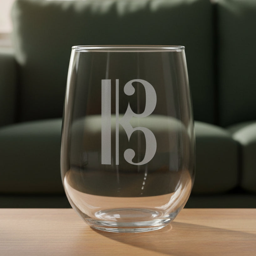 Bass Clef stemless wine glass with a green couch behind it
