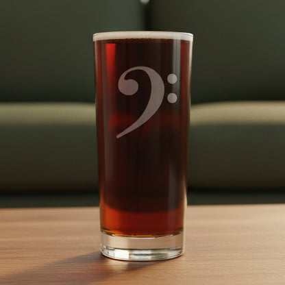 Cooler glass with an etched bass clef  on a wooden surface with a green couch in the background
