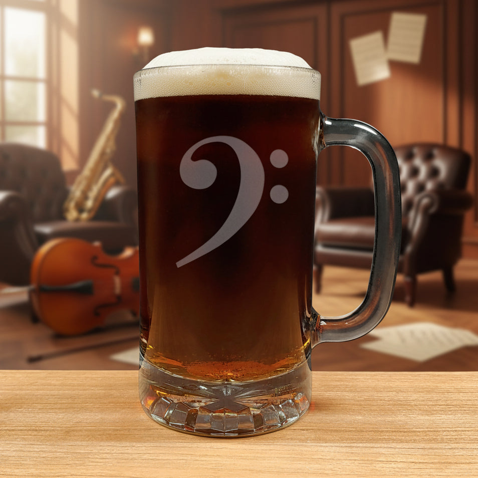 Glass mug with a bass clef engraving filled with dark beer on a wooden surface with a music room in the background