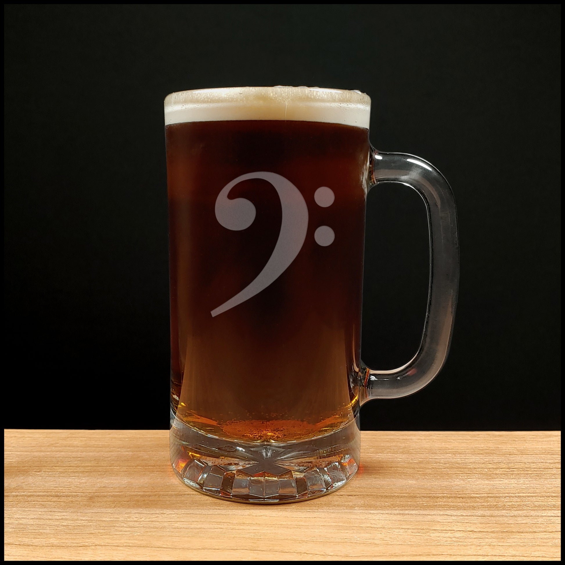 Glass mug with a bass clef engraving filled with dark beer on a wooden surface 