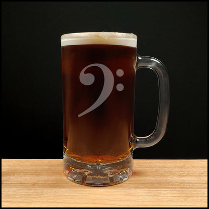 Glass mug with a bass clef engraving filled with dark beer on a wooden surface 