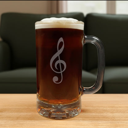 Glass mug with a treble clef engraving filled with dark beer on a wooden surface with a green couch in the background