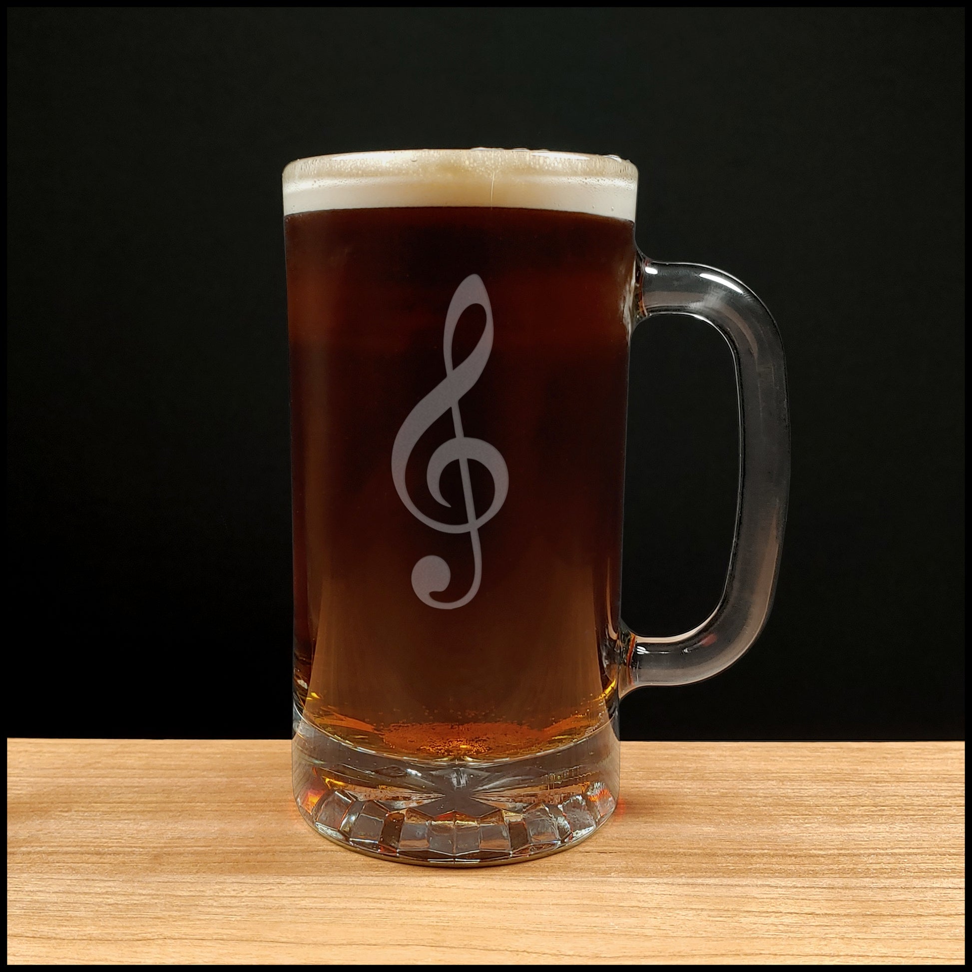 Glass mug with a treble clef engraving filled with dark beer on a wooden surface 