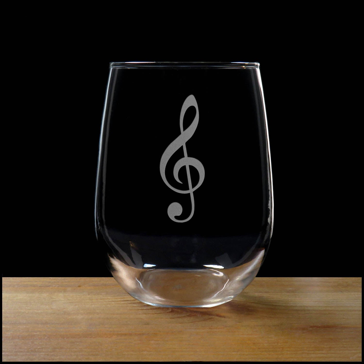 Treble Clef with Heart stemless wine glass on a wood surface with a black background
