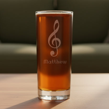 Cooler glass with an etched treble clef on a wooden surface with a green couch in the background