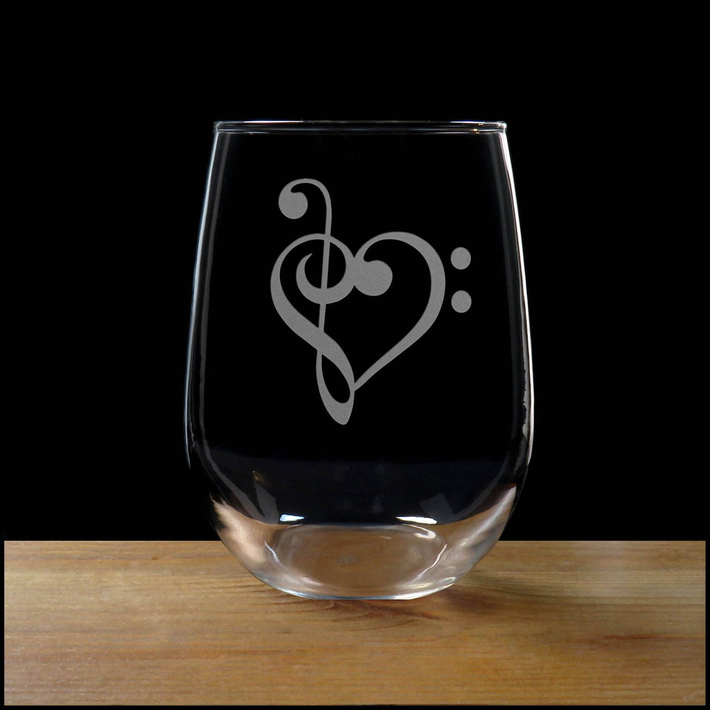 Treble Clef Heart stemless wine glass on a wood surface with a black background
