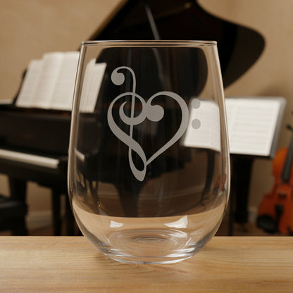 Stemless wine glass with a treble clef, bass clef Heart etching on a wooden surface with a music room in the background