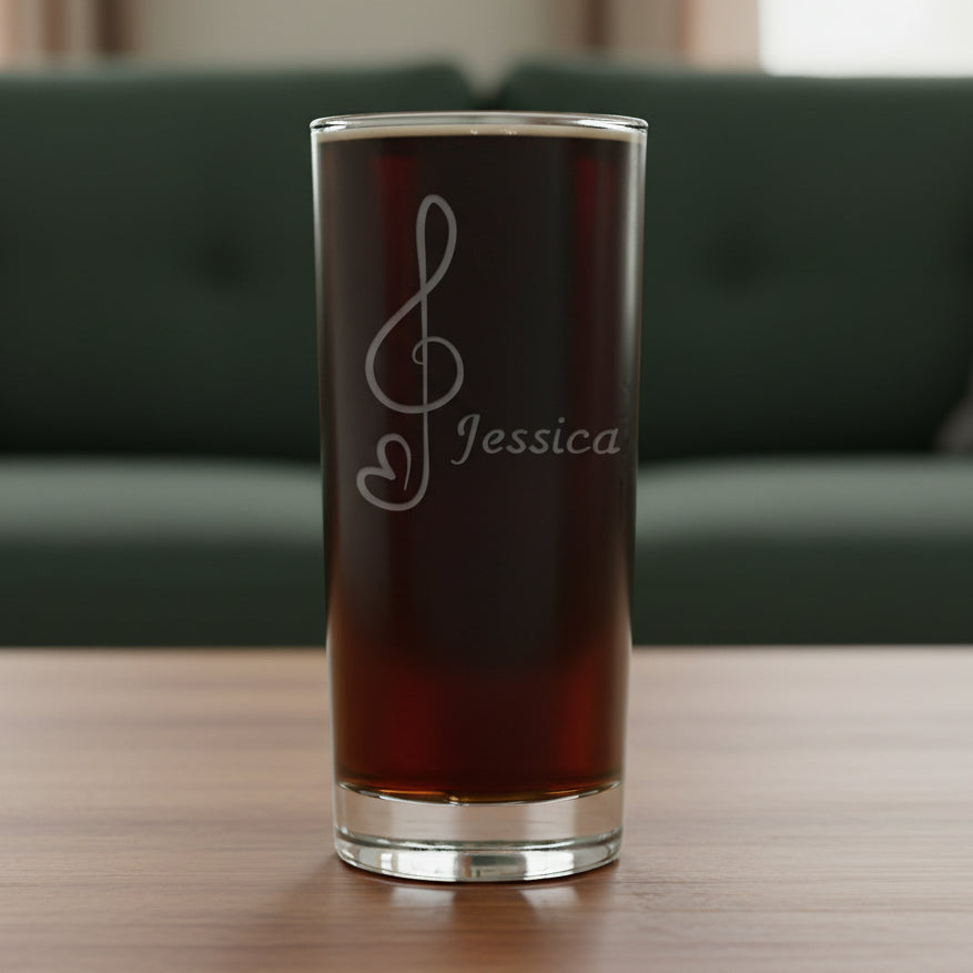 Cooler glass with an etched treble clef with heart tail on a wooden surface with a green couch in the backgrounde 