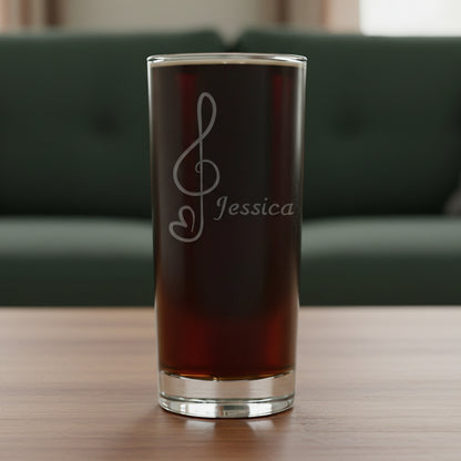 Cooler glass with an etched treble clef with heart tail on a wooden surface with a green couch in the backgrounde 