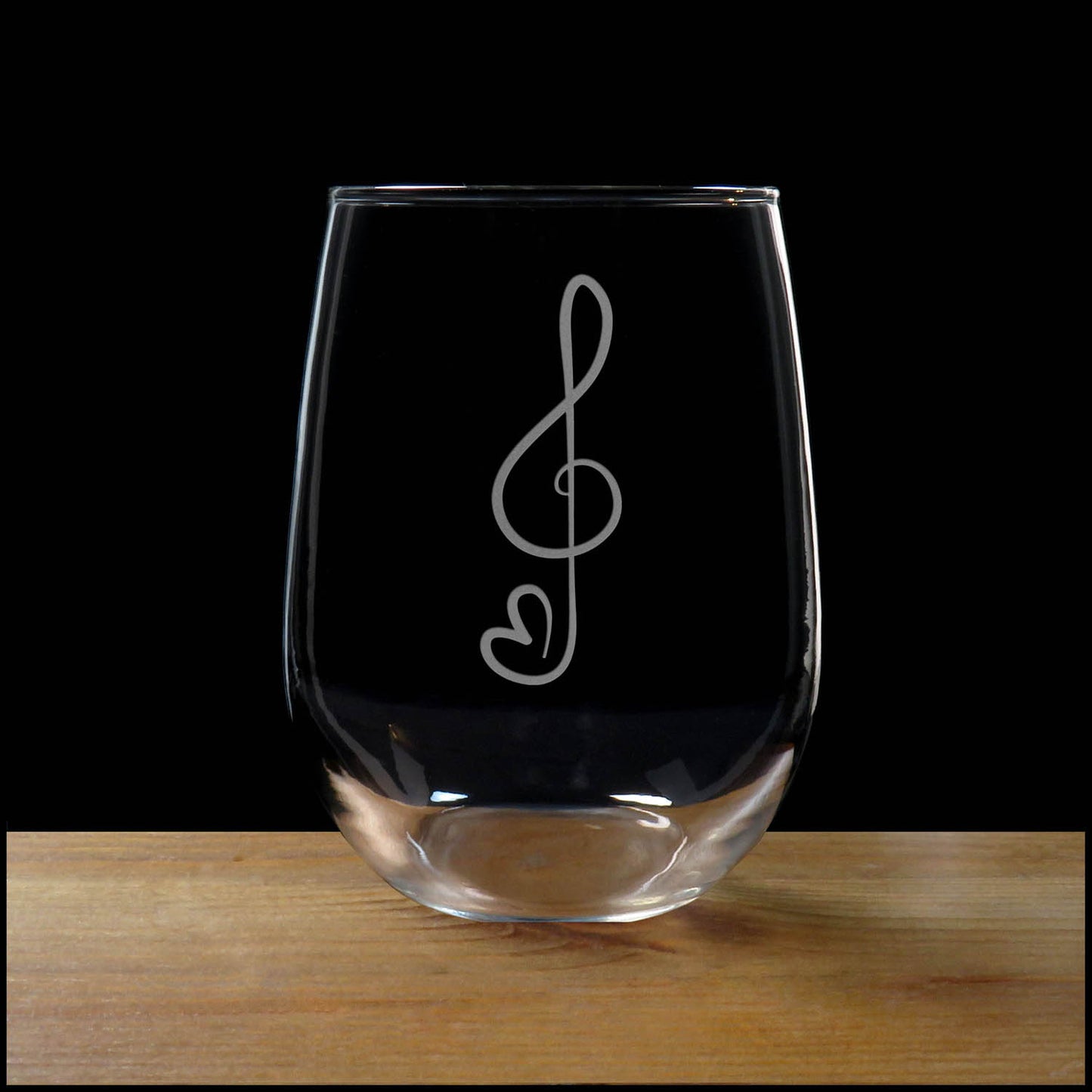 Treble Clef with a heart tail stemless wine glass on a wood surface with a black background