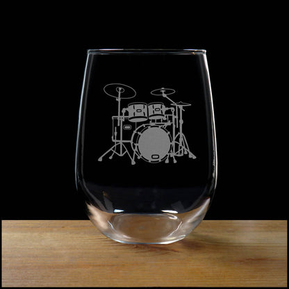 Stemless wine glass with etched Drum Set Design on a wood surface with a black background