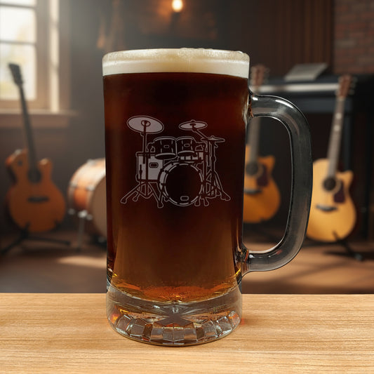 Glass mug with a drum set engraving filled with dark beer on a wooden surface with a music room in the background