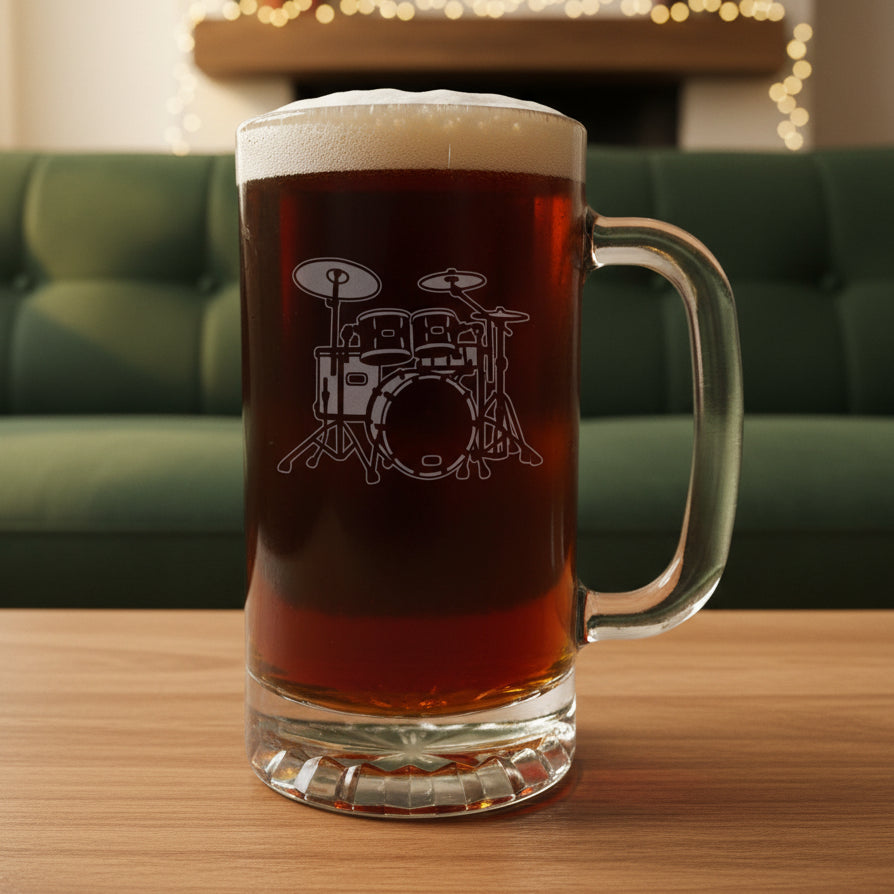 Glass mug with a drum set engraving filled with dark beer on a wooden surface with a green couch in the background