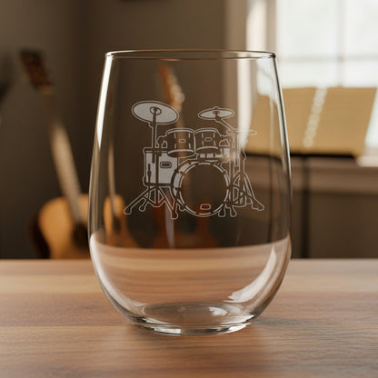 Stemless wine glass with a Drum Set etching on a wooden surface with a music room in the background