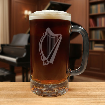 Glass mug with a harp engraving filled with dark beer on a wooden surface with a music room in the background