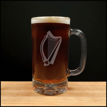 Glass mug with a harp engraving filled with dark beer on a wooden surface 