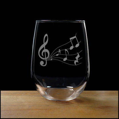 Stemless wine glass with etched Music Staff Design on a wood surface with a black background