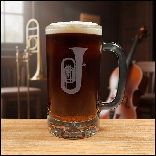 Glass mug with a tuba engraving filled with dark beer on a wooden surface with a music room in the background